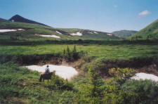 A rider passes by patches of snow during a spring day in the mountains.